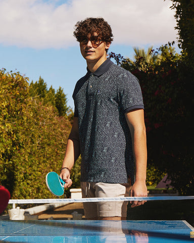 model with sunglasses wearing psycho bunny polo and playing ping pong